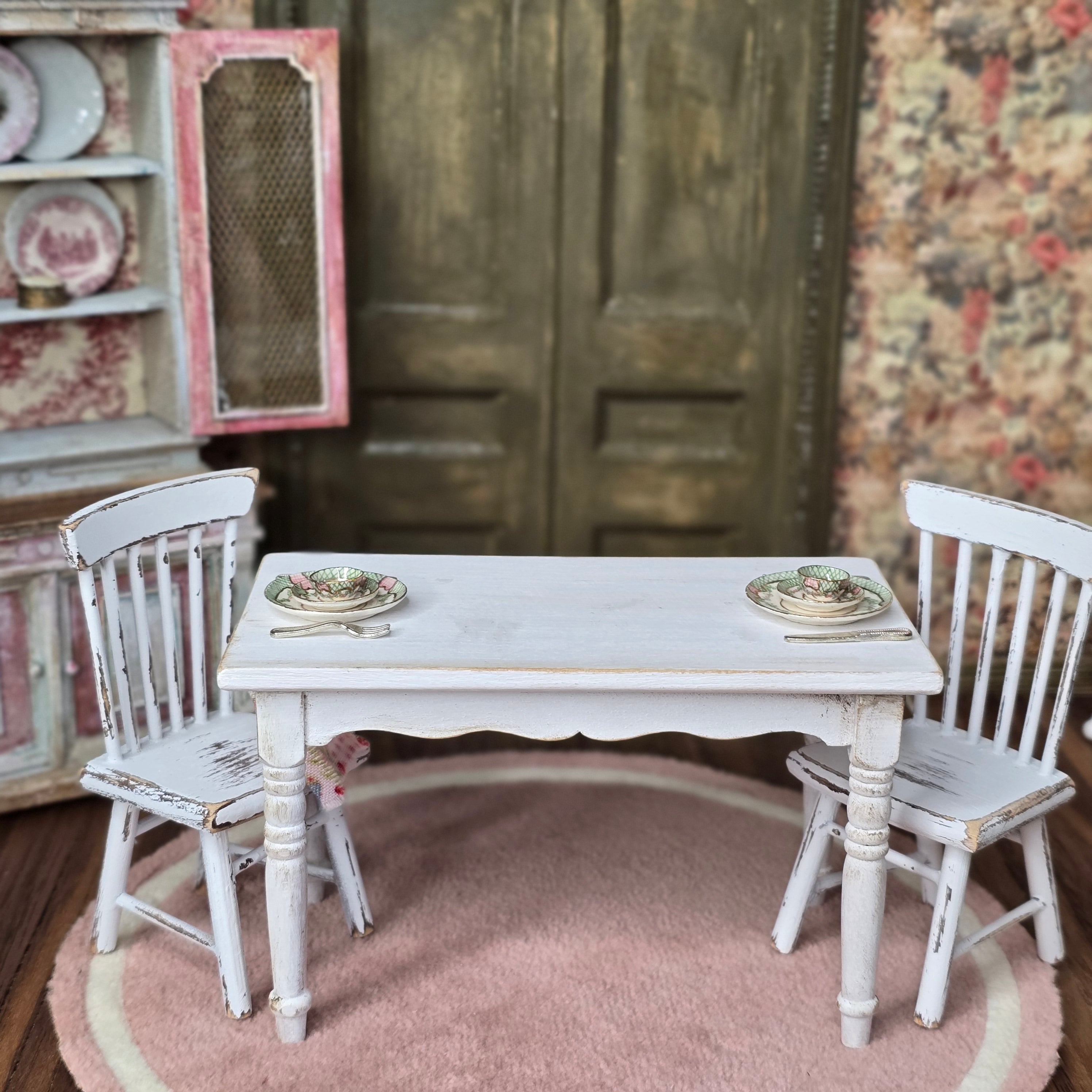 Miniature white table with two chairs in a decorative setting