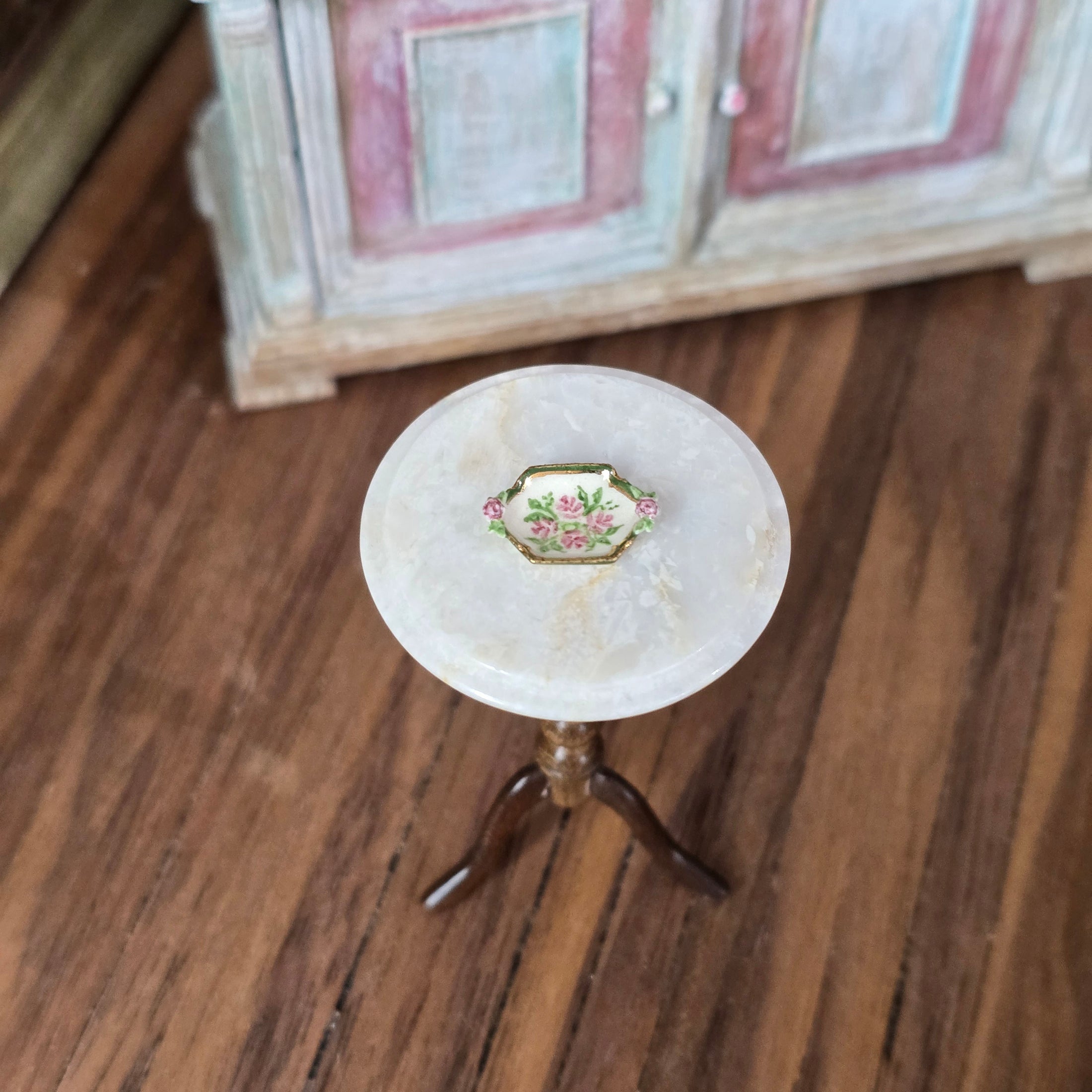 Small round table with a decorative dish on a wooden floor
