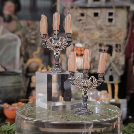 Decorative candelabra with candles on a clear stand against a Halloween-themed background.