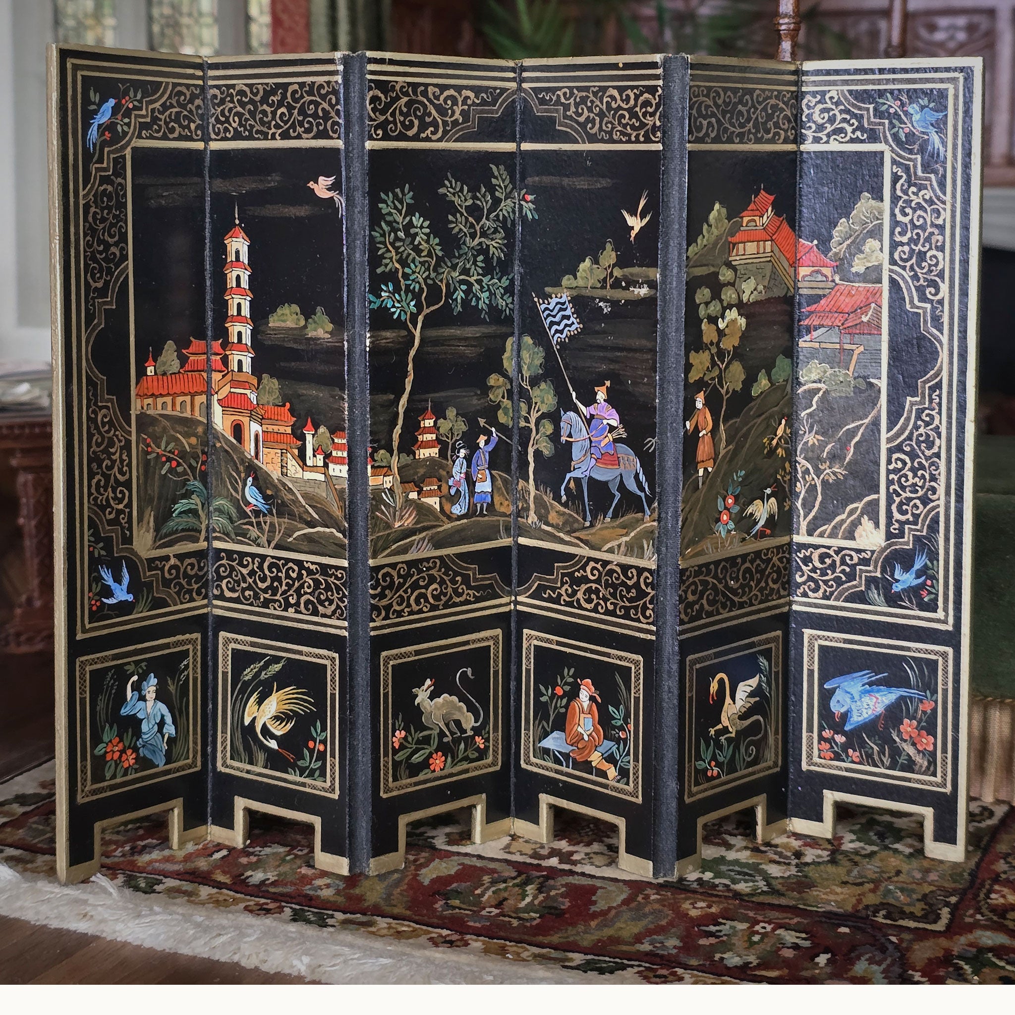Decorative screen with intricate designs of people, animals, and landscapes on a dark background.