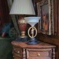 Load image into Gallery viewer, Decorative sculpture with a metal male figure on a black base in a warm, indoor miniature setting, with a lamp and framed picture in the background.
