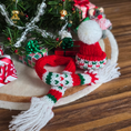 Load image into Gallery viewer, Dollhouse miniature Knitted scarf and hat with a Christmas tree in the background.

