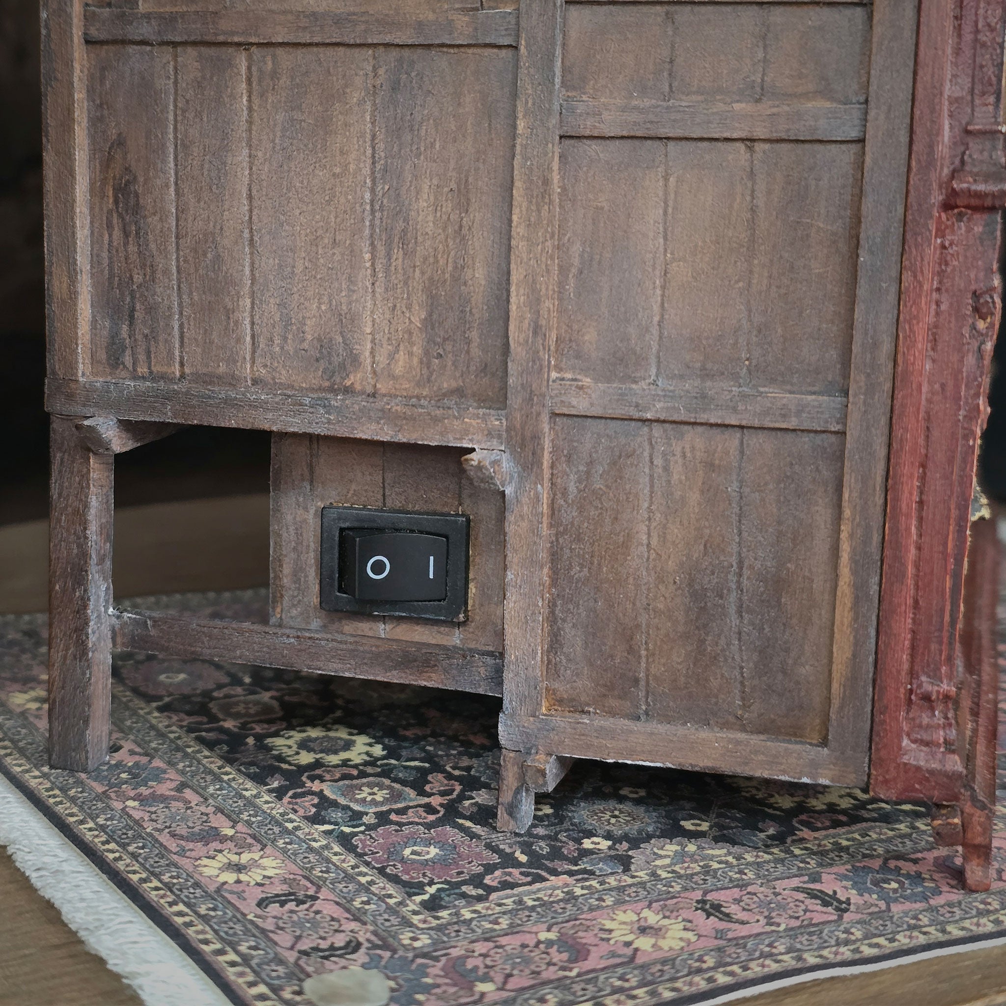 Vintage wooden side of alcove bed with a power outlet on a patterned rug