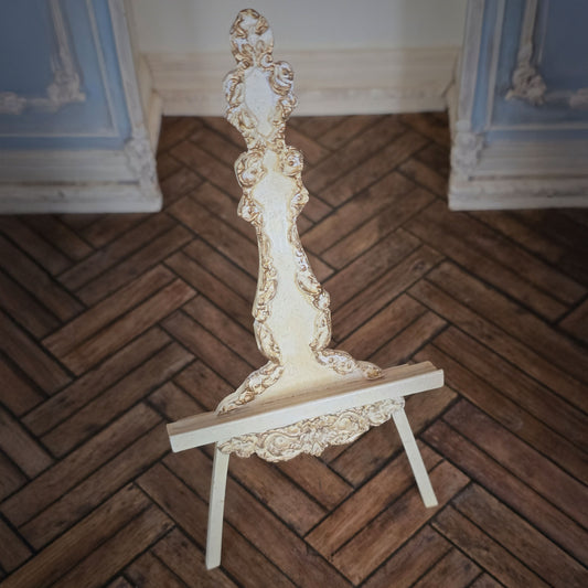 Decorative carved miniature easel with intricate design on a wooden floor