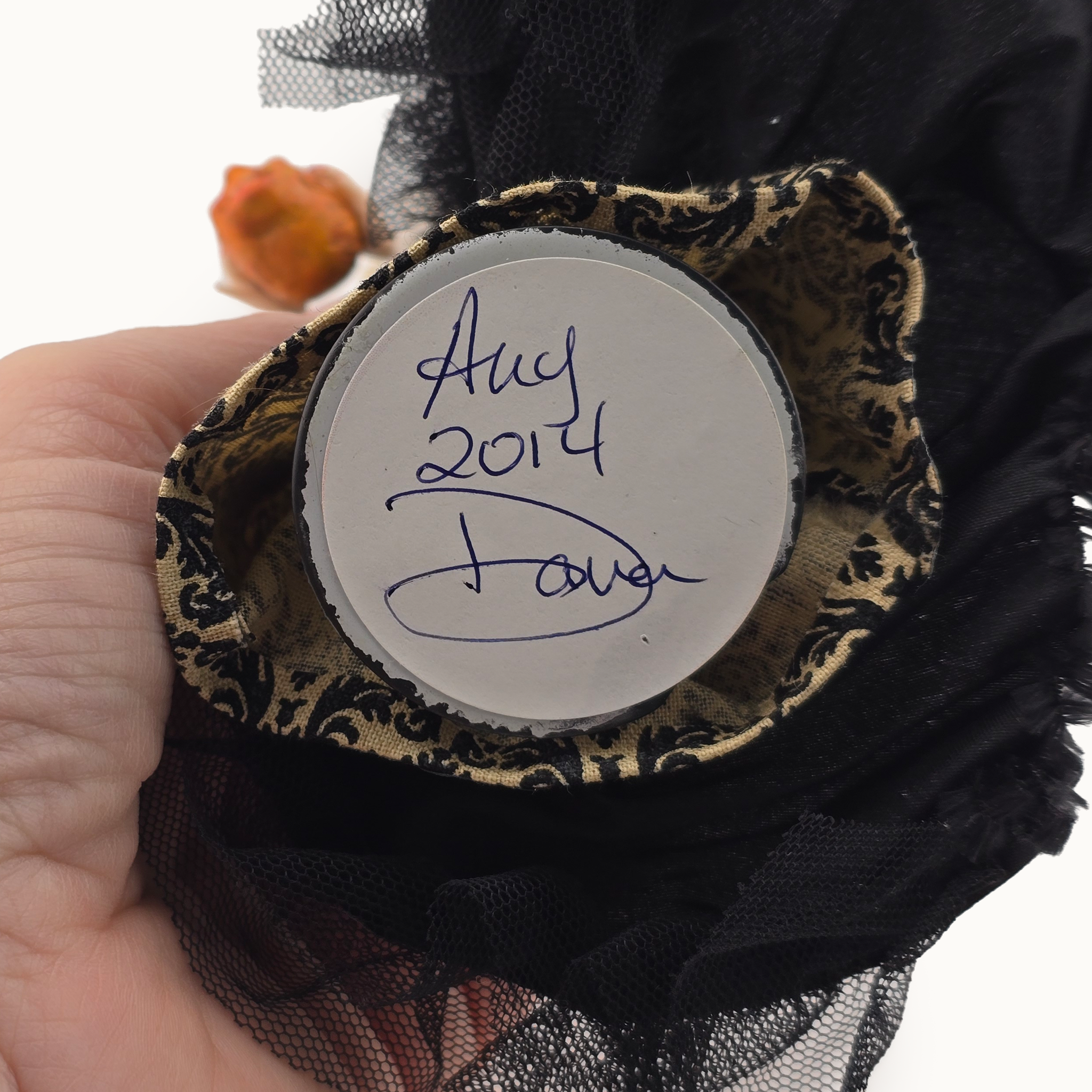 Decorative item with a label reading 'Aug 2014 Davis' held by a hand.