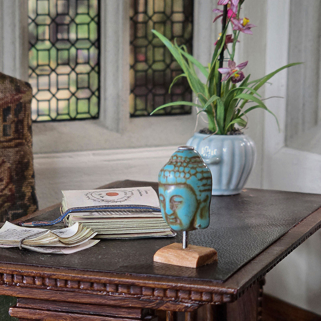 Decorative Miniature decorative head statue on a wooden table with a vase of flowers in the background