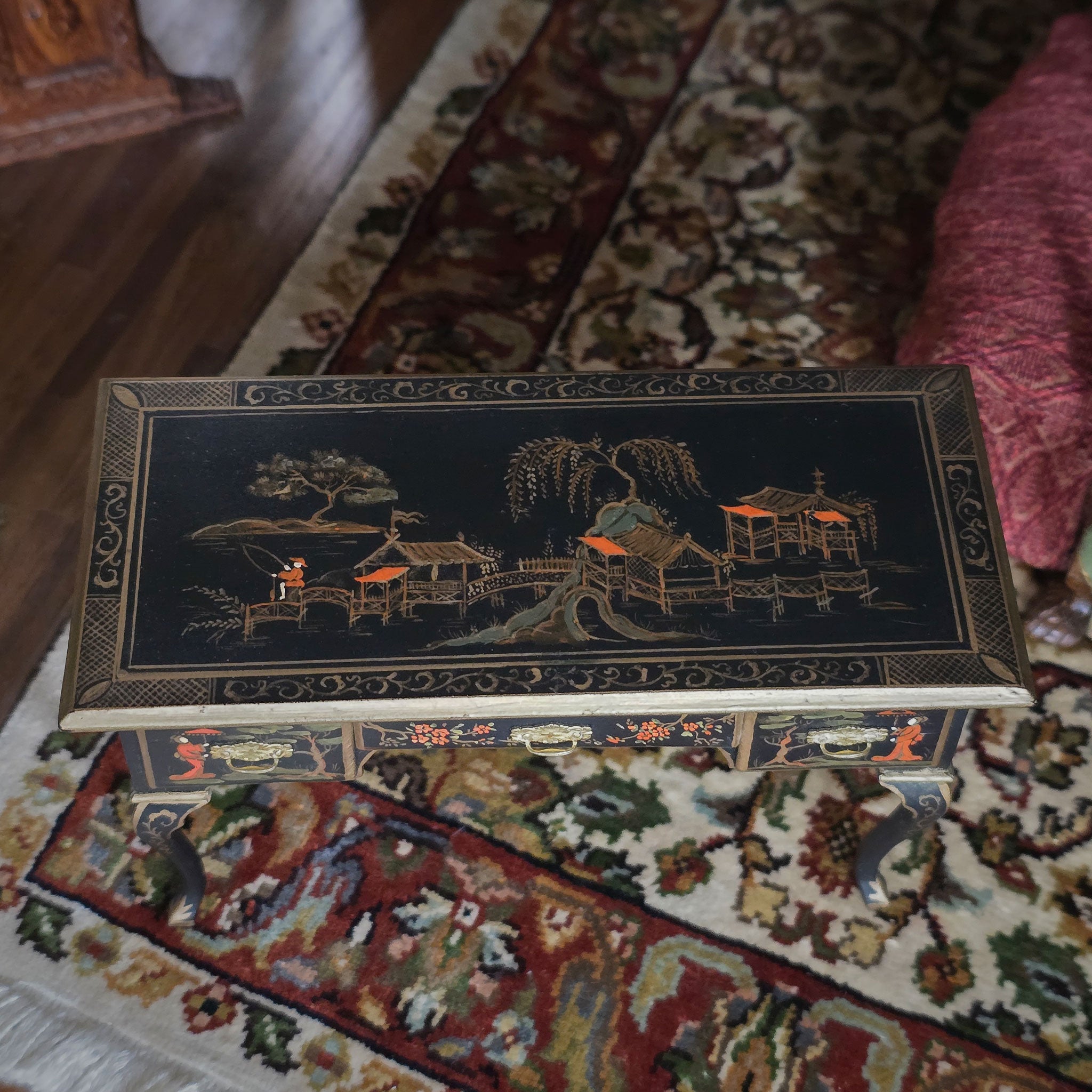 Chinoiserie miniature desk with intricate designs on a patterned rug