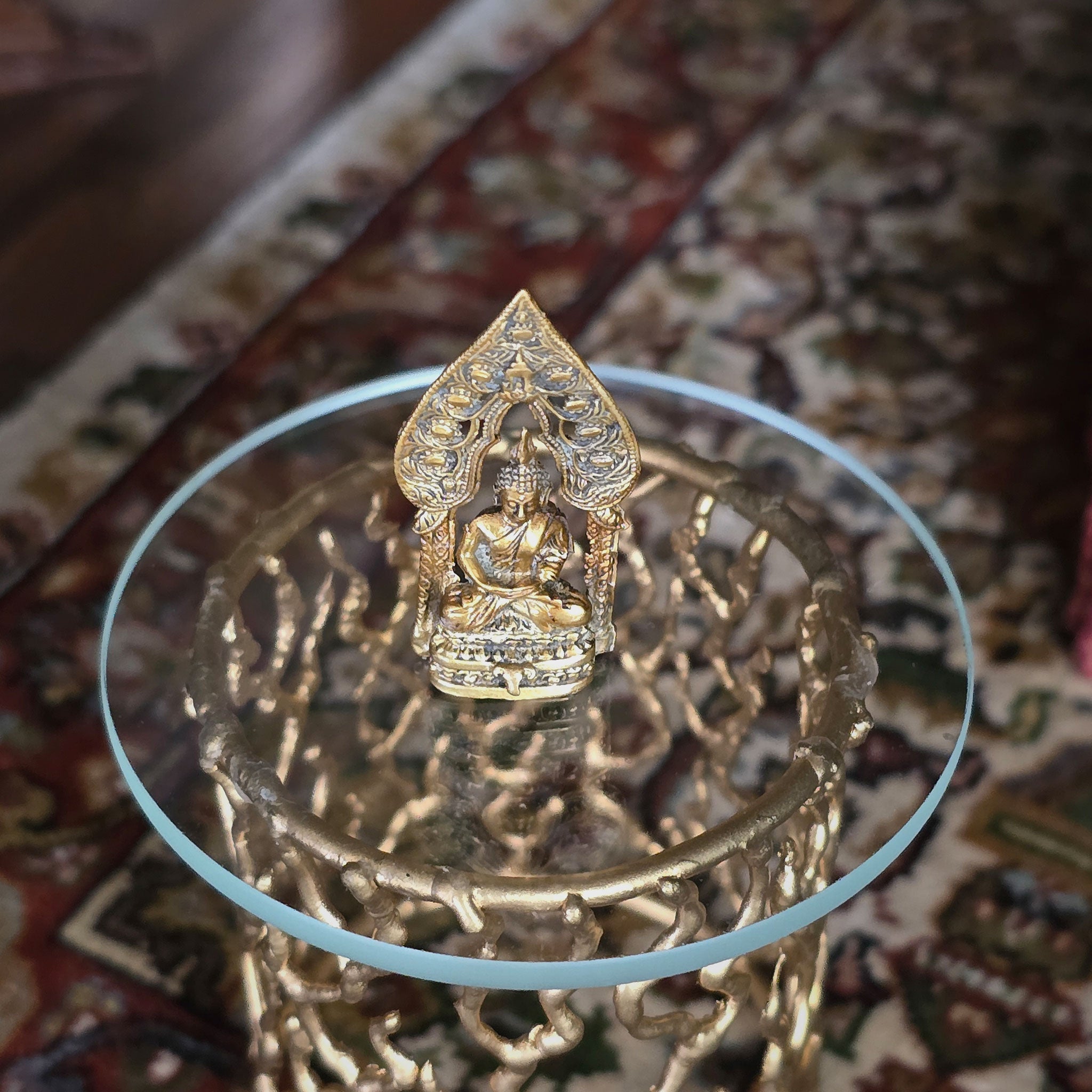 Gold-colored Buddha statue on a decorative stand with intricate patterns