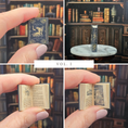 Load image into Gallery viewer, Collage of a miniature book held by a hand with a detailed interior, set against a bookshelf background.
