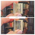 Load image into Gallery viewer, Miniature book held between fingers with a blurred bookshelf background
