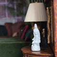 Load image into Gallery viewer, White statue of a figure on a wooden shelf with a lamp in the background
