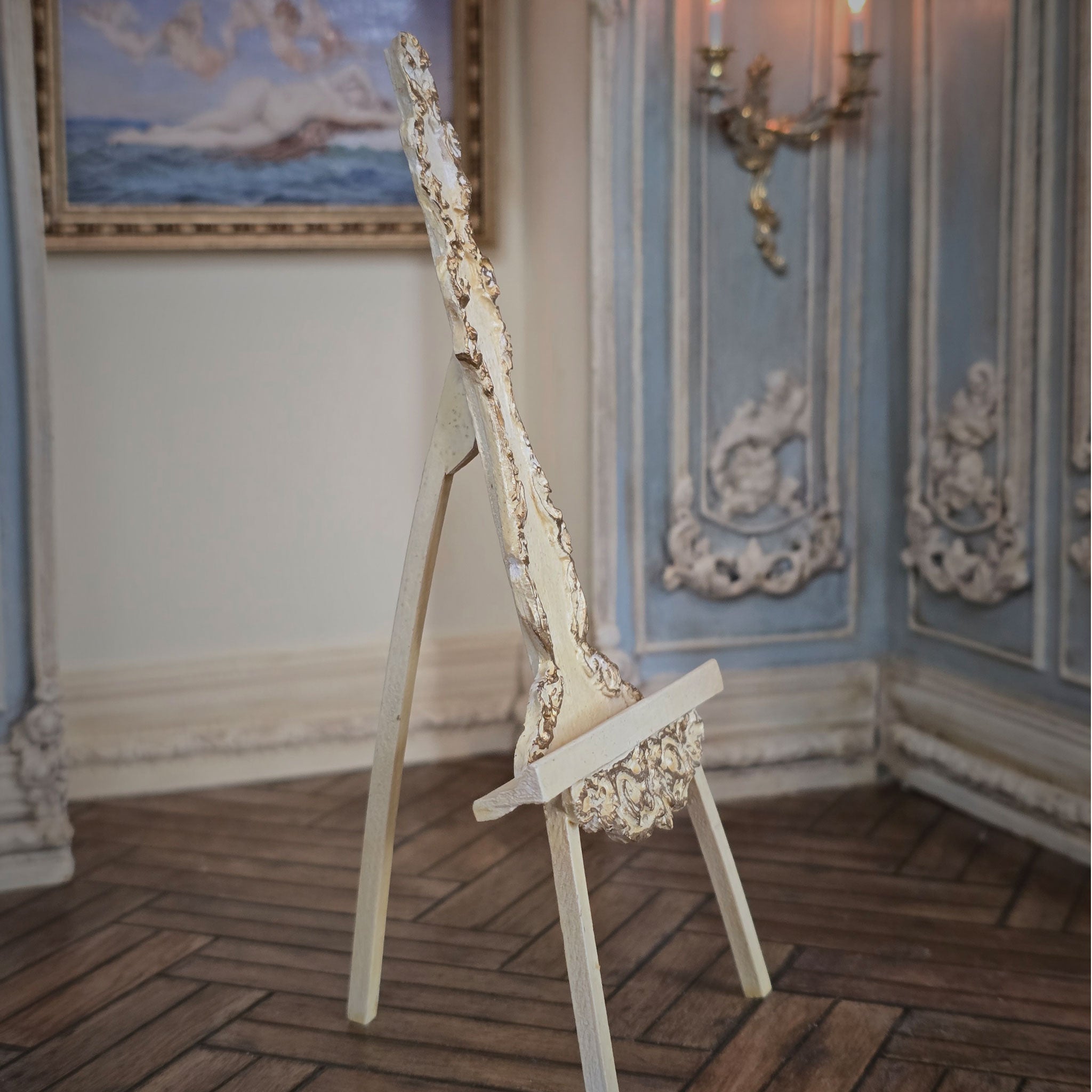 Decorative easel in an ornate room with blue walls and a painting.