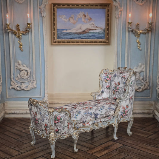 Decorative floral chaise bench in an ornate room with wall sconces and a painting.
