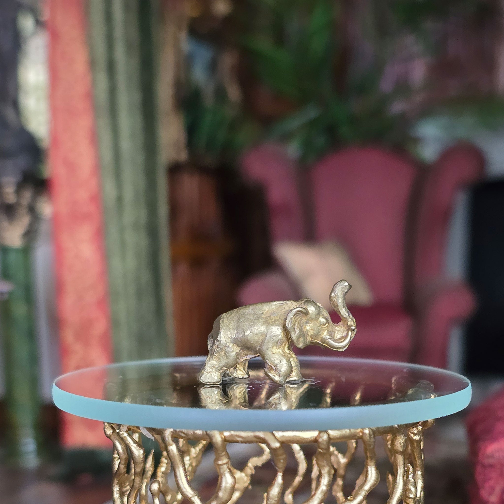 Gold elephant figurine on a round glass table with a blurred background