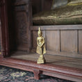 Load image into Gallery viewer, Gold Buddha statue on a wooden shelf with a wooden cabinet in the background
