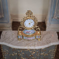 Load image into Gallery viewer, Decorative gold clock on a marble surface with a blurred background
