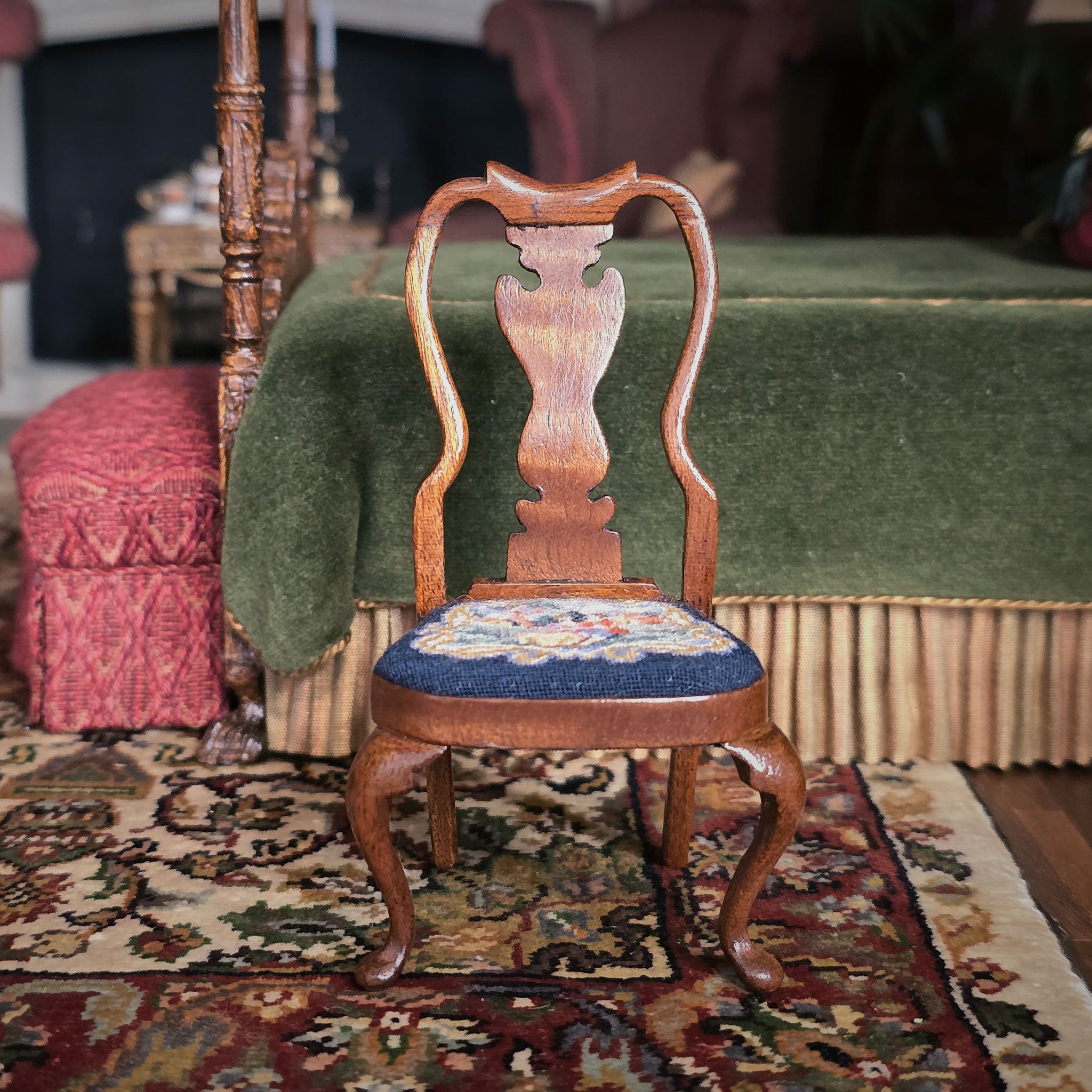 Wooden chair with a scenic petit point seat on a rug in a room with furniture and decor.