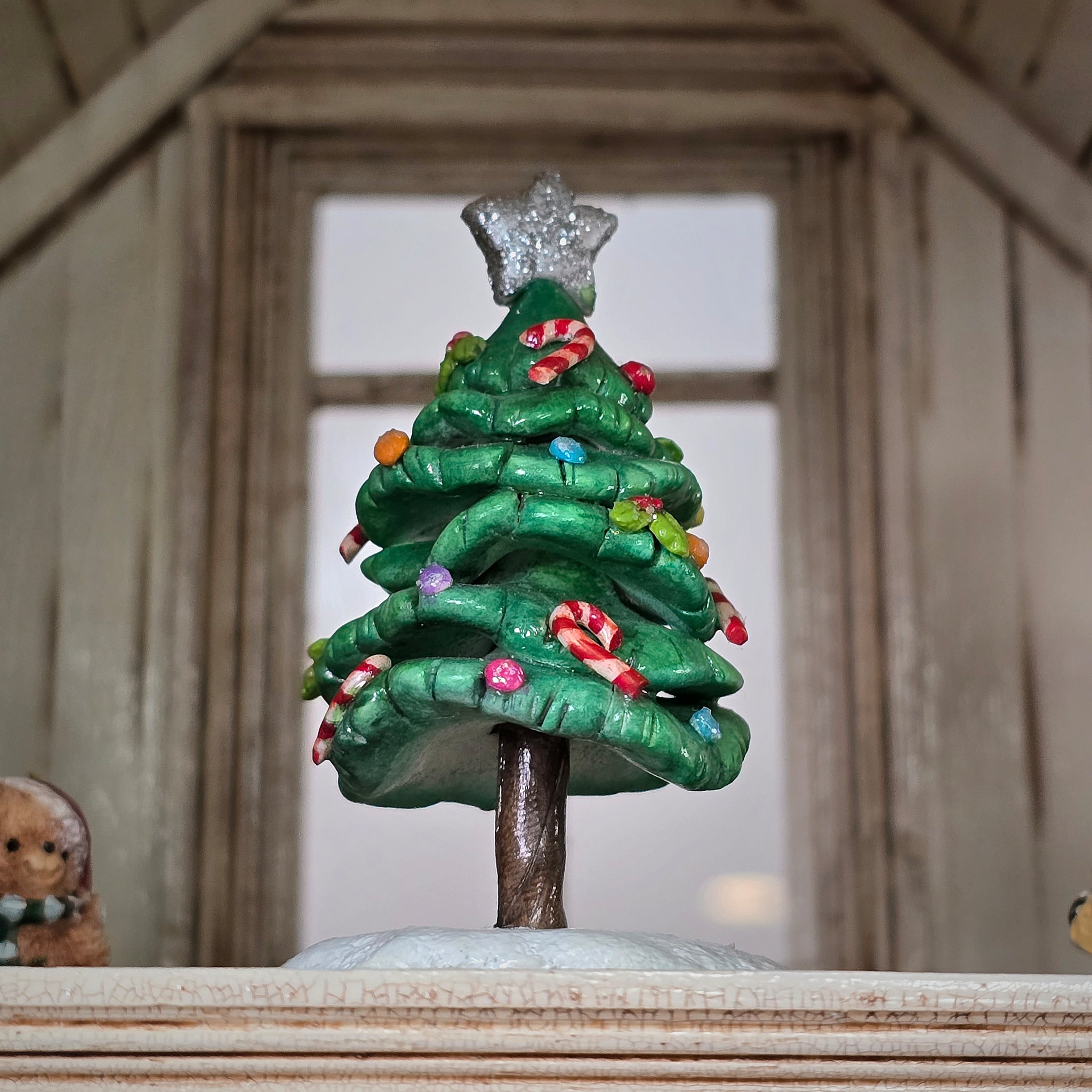 Decorative Christmas tree figurine with candy decorations on a wooden surface.