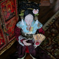 Load image into Gallery viewer, Traditional doll in ornate clothing holding a fan, with a blurred background
