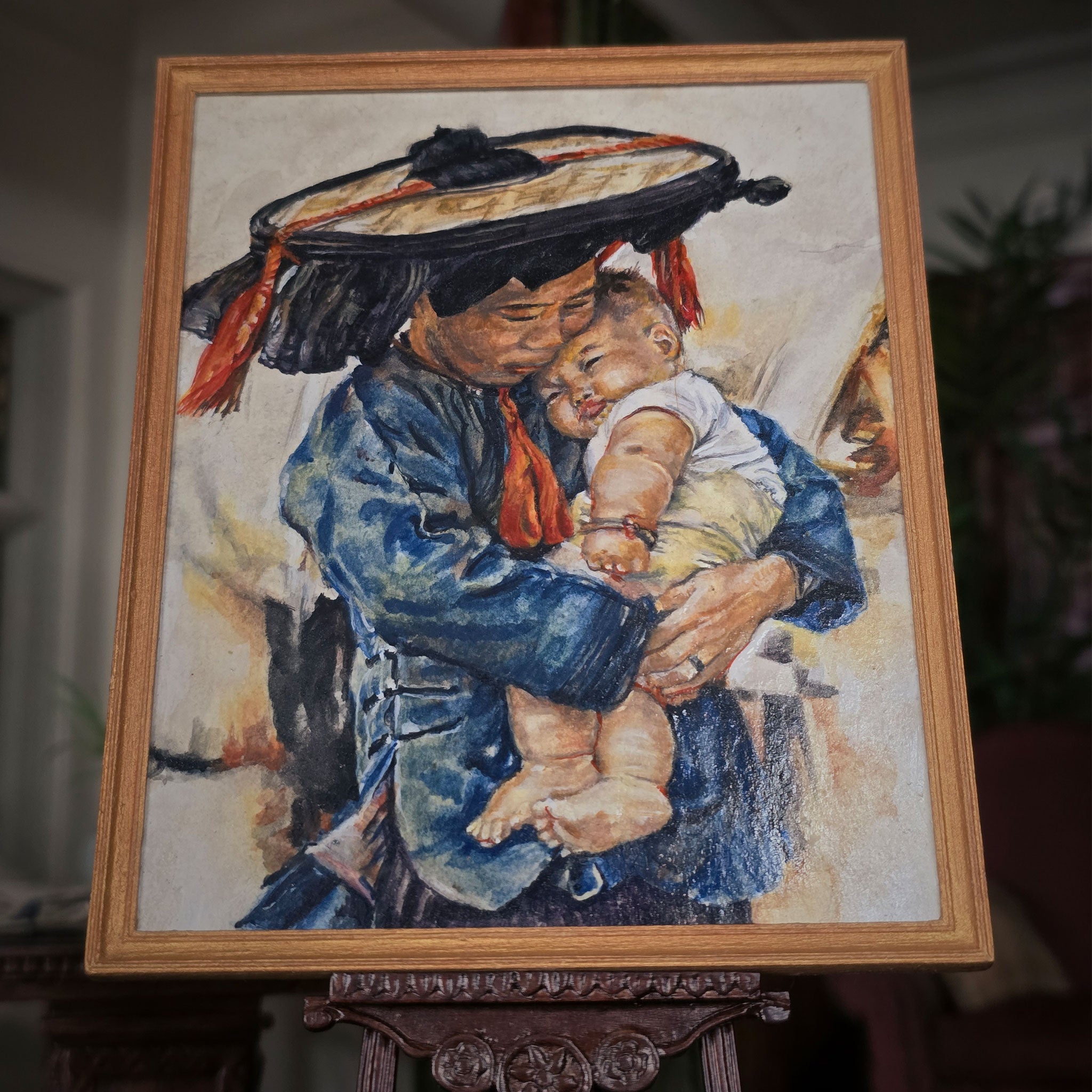 Framed artwork of a woman holding a child with a wooden frame.