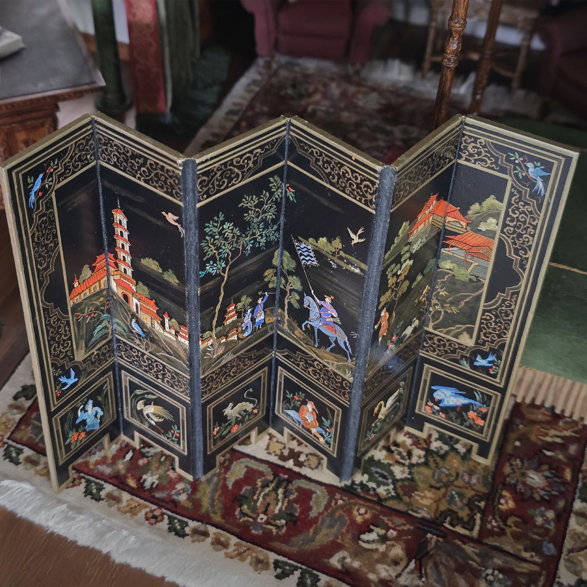 Decorative folding screen with intricate designs on a patterned rug