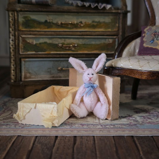 Pink stuffed bunny with a blue bow tie sitting in a vintage room.