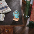 Load image into Gallery viewer, Small turquoise ceramic vase on a wooden stand with books and a green column in the background. Miniature
