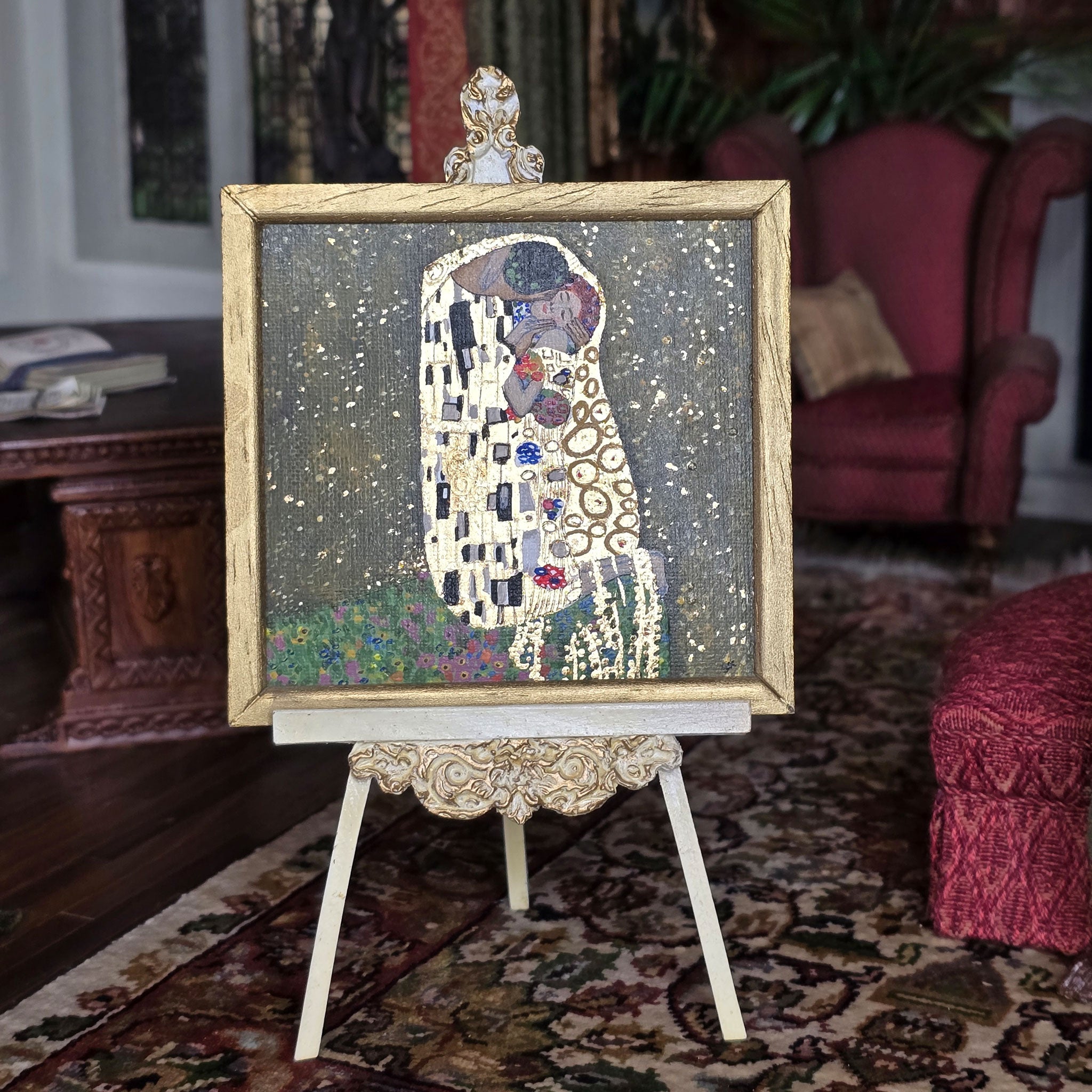 Decorative painting of 'The Kiss' by Gustav Klimt on an easel in a room setting, by Sam Kelm in miniature