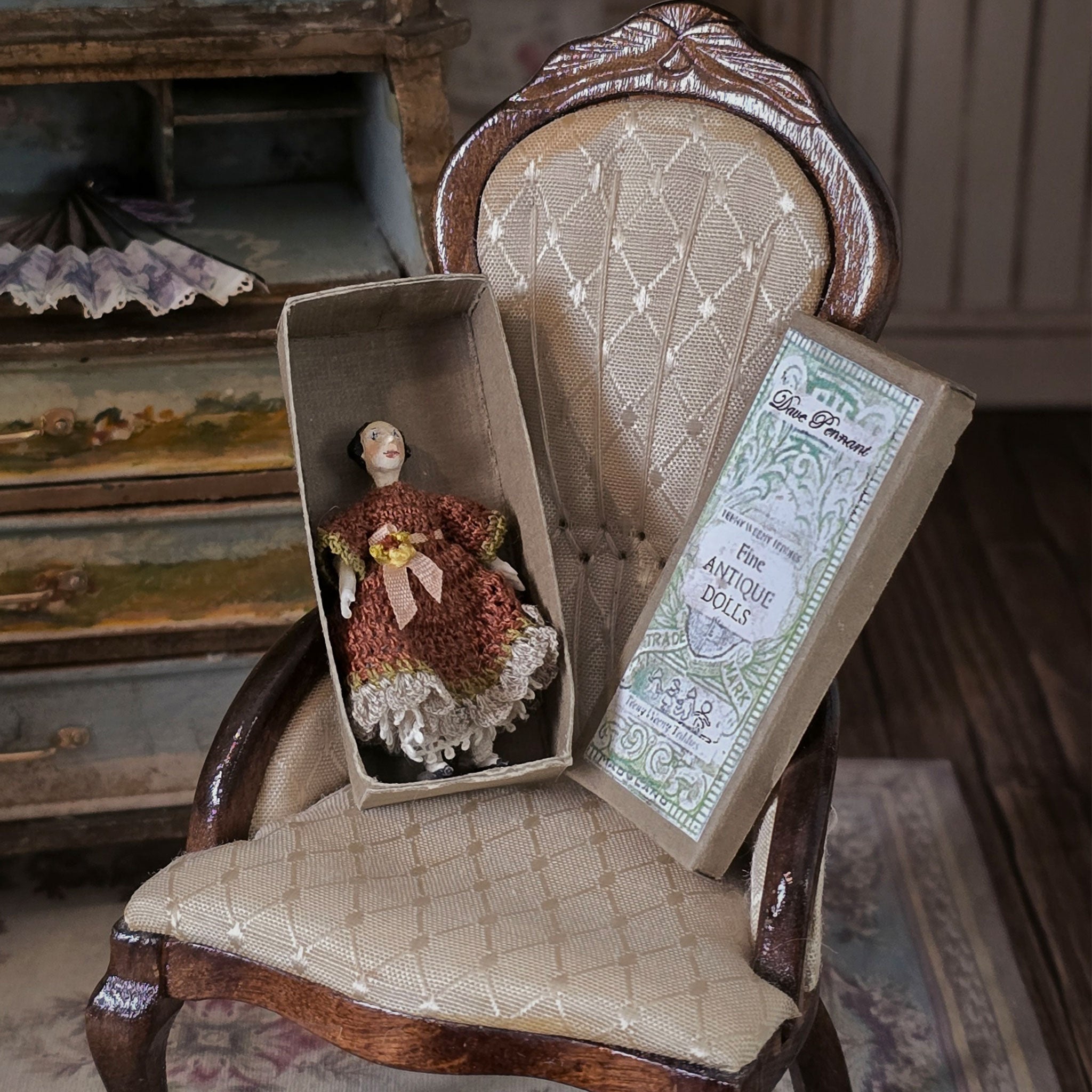 Vintage doll in a box on an antique chair with a decorative background