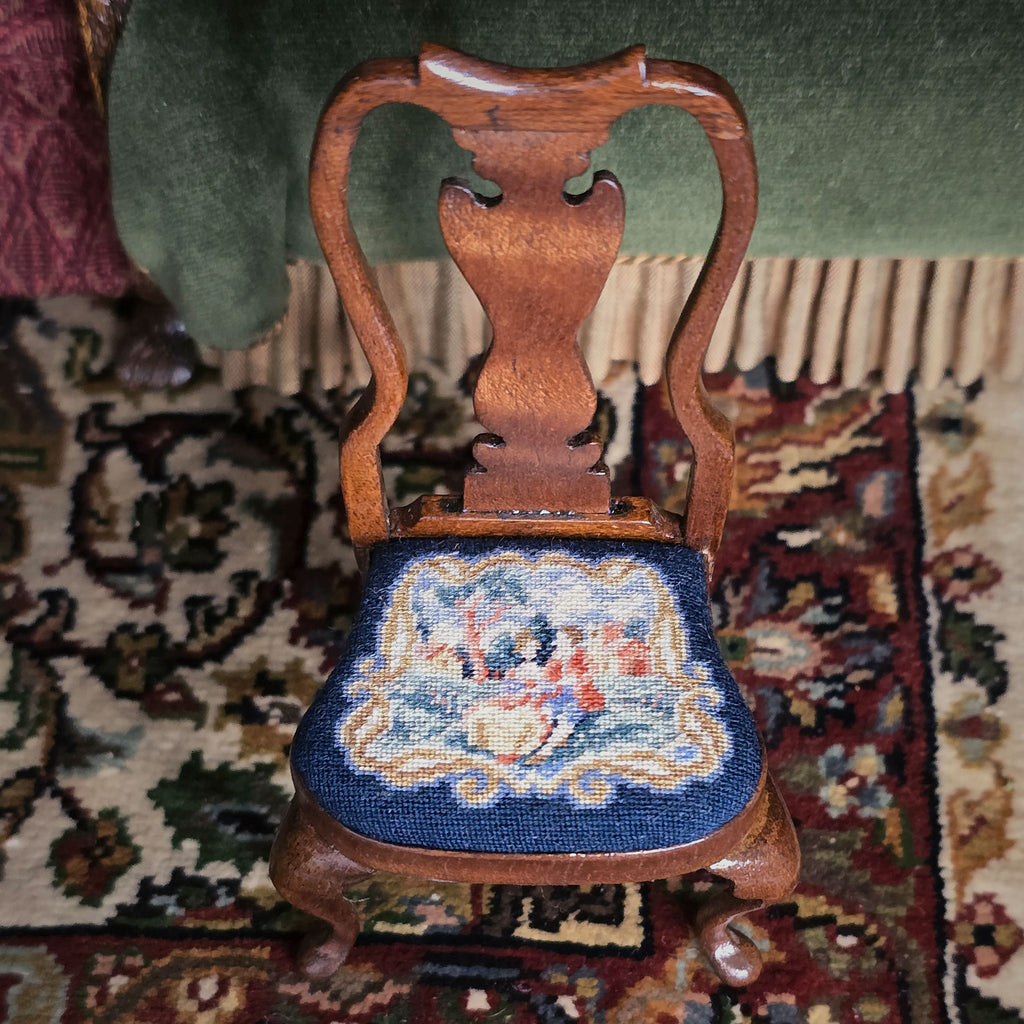 Wooden chair with a petit point needlepoint scenic seat on a patterned rug