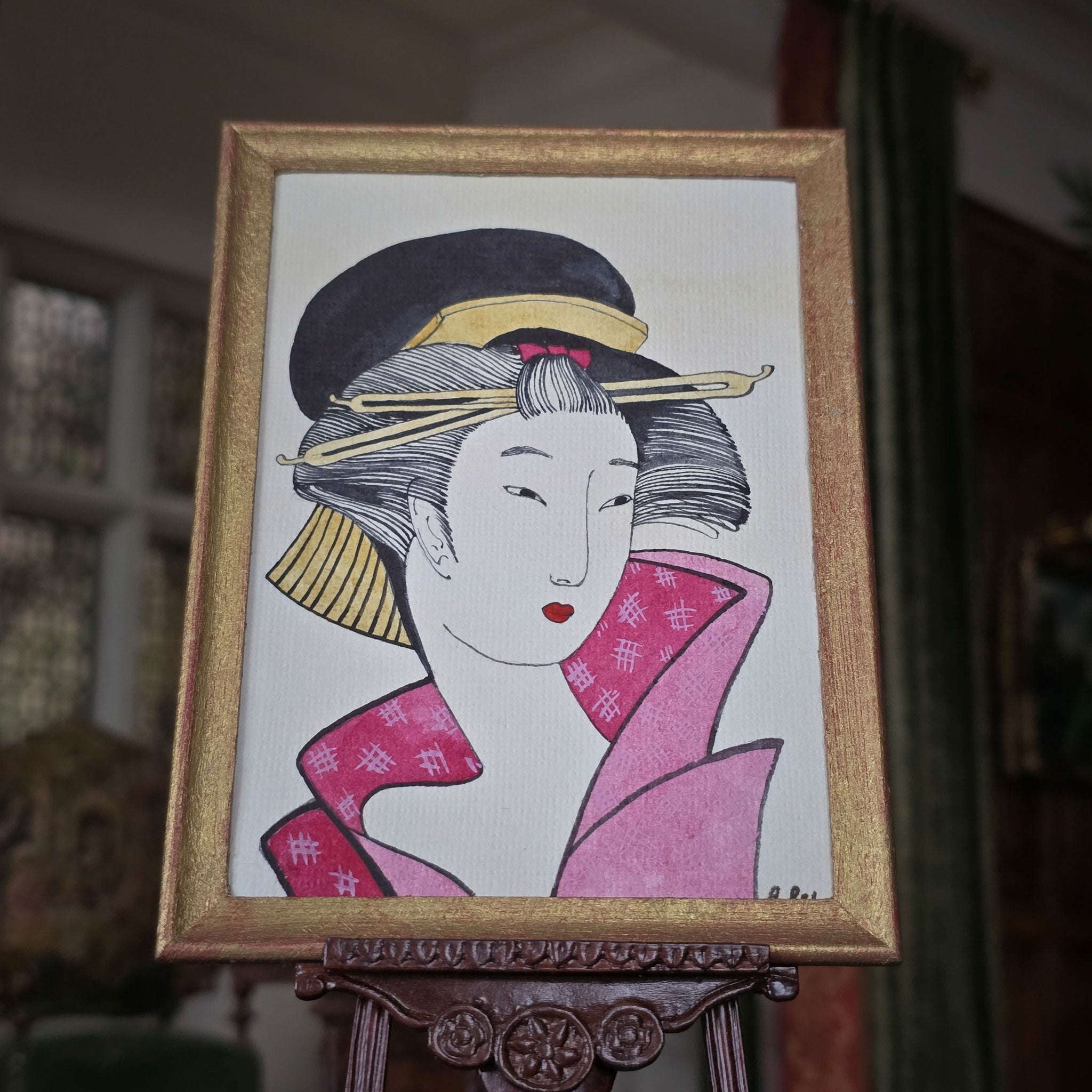 Framed artwork of a woman in traditional attire on an easel. Alexandra R.
