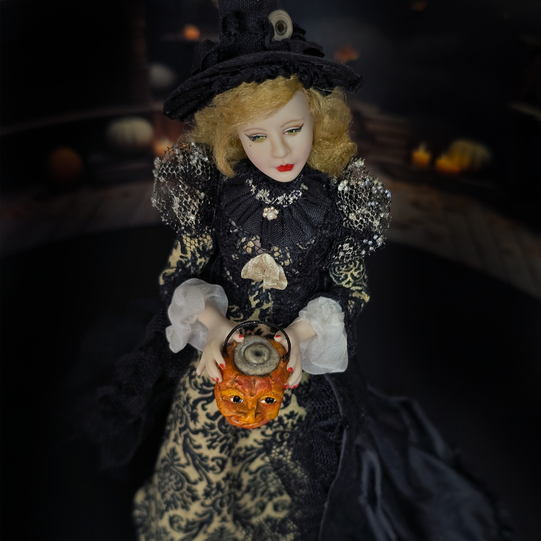 beautiful witch doll in a dark gown with a hat, holding a lantern with a pumpkin design, against a dark background.