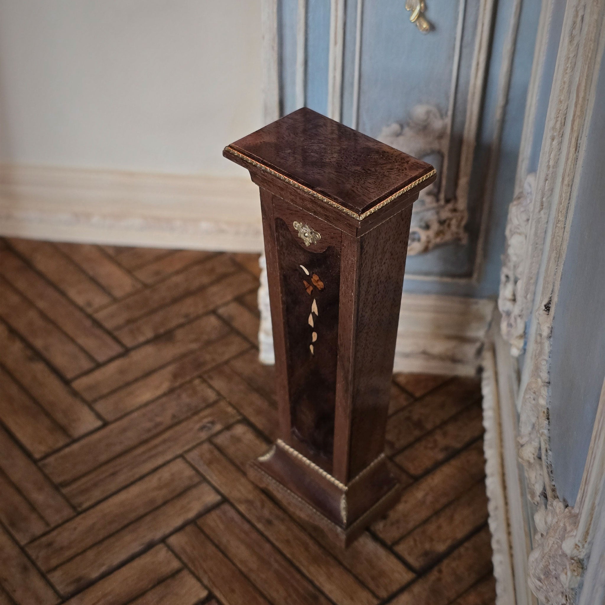 Wooden pedestal on a wooden floor with decorative elements in the background