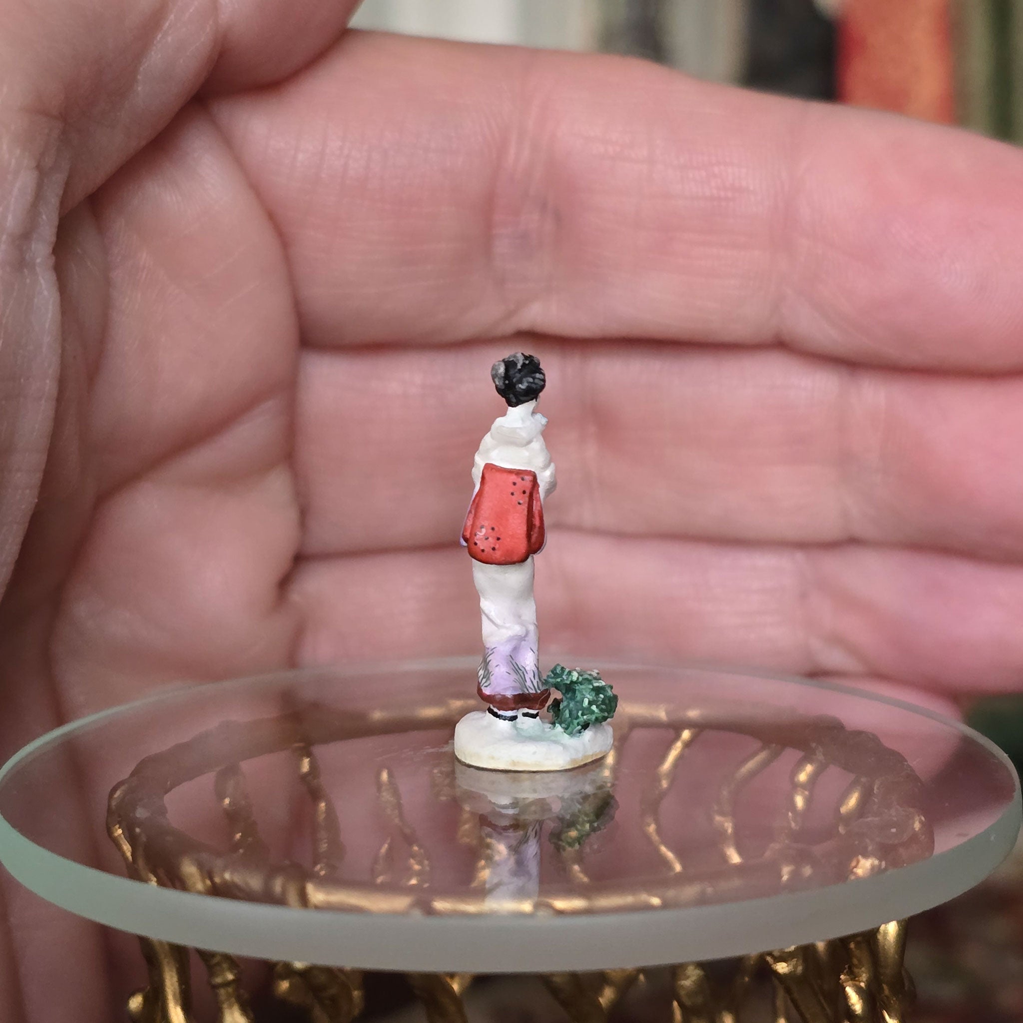 Small figurine on a transparent stand held in a hand