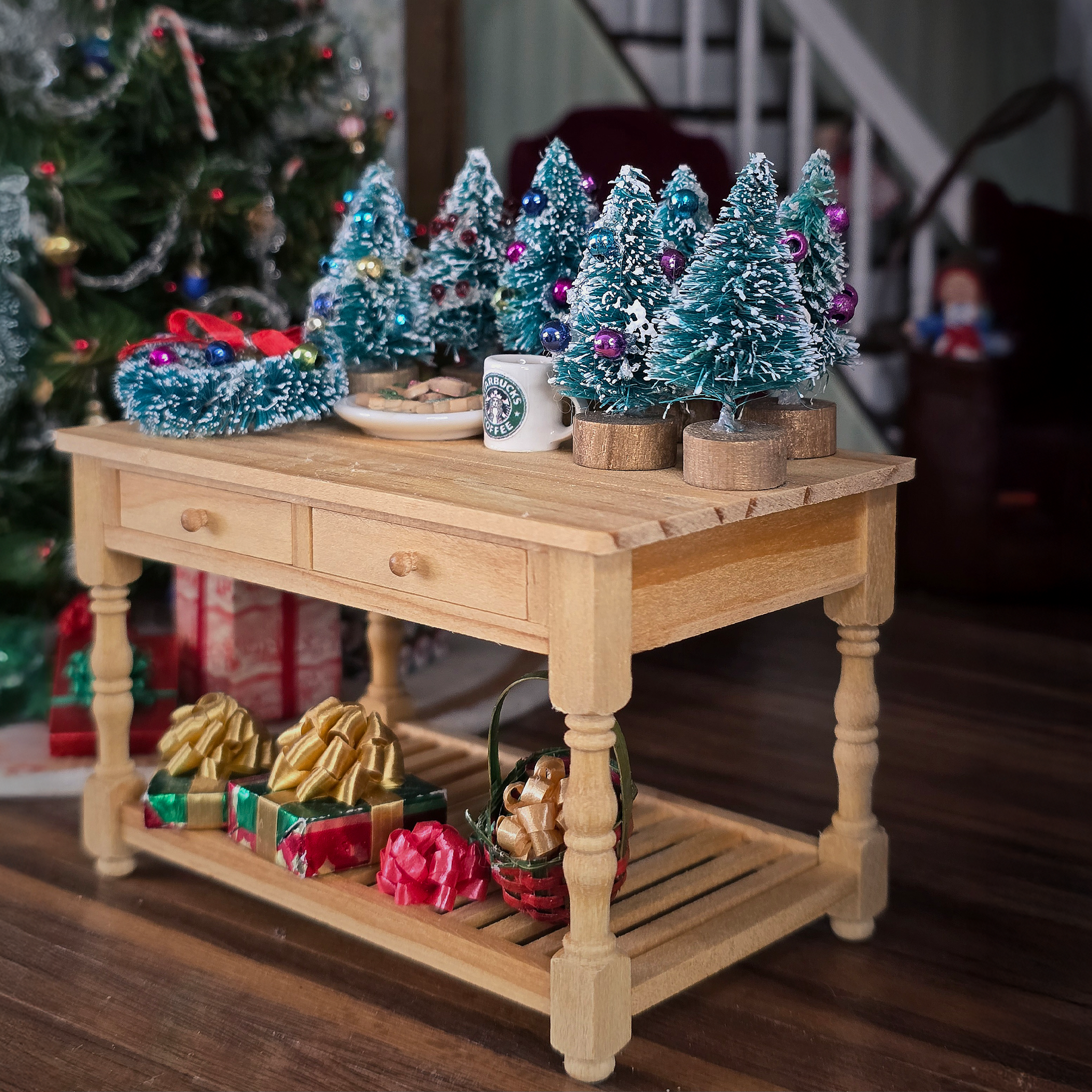 Wooden table with Christmas decorations including small trees, a mug, and gift boxes.