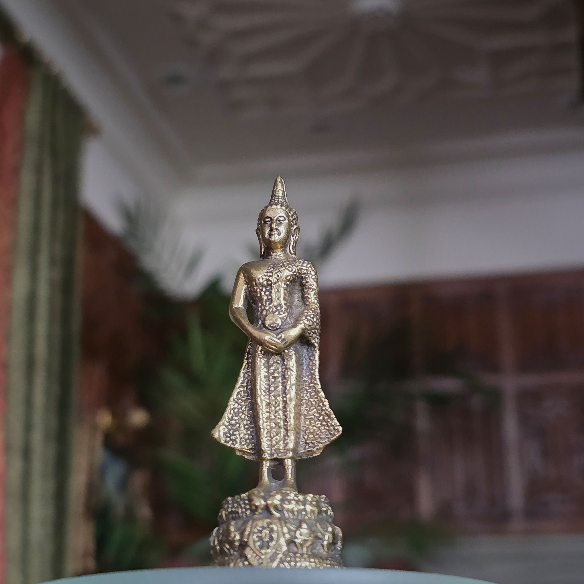 Bronze Buddha statue on a pedestal with a blurred background