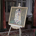 Load image into Gallery viewer, Artistic depiction of 'The Kiss' by Gustav Klimt in miniature, on a decorative stand with a vintage room background.
