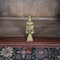 Load image into Gallery viewer, Gold statue on a wooden surface with a patterned rug below

