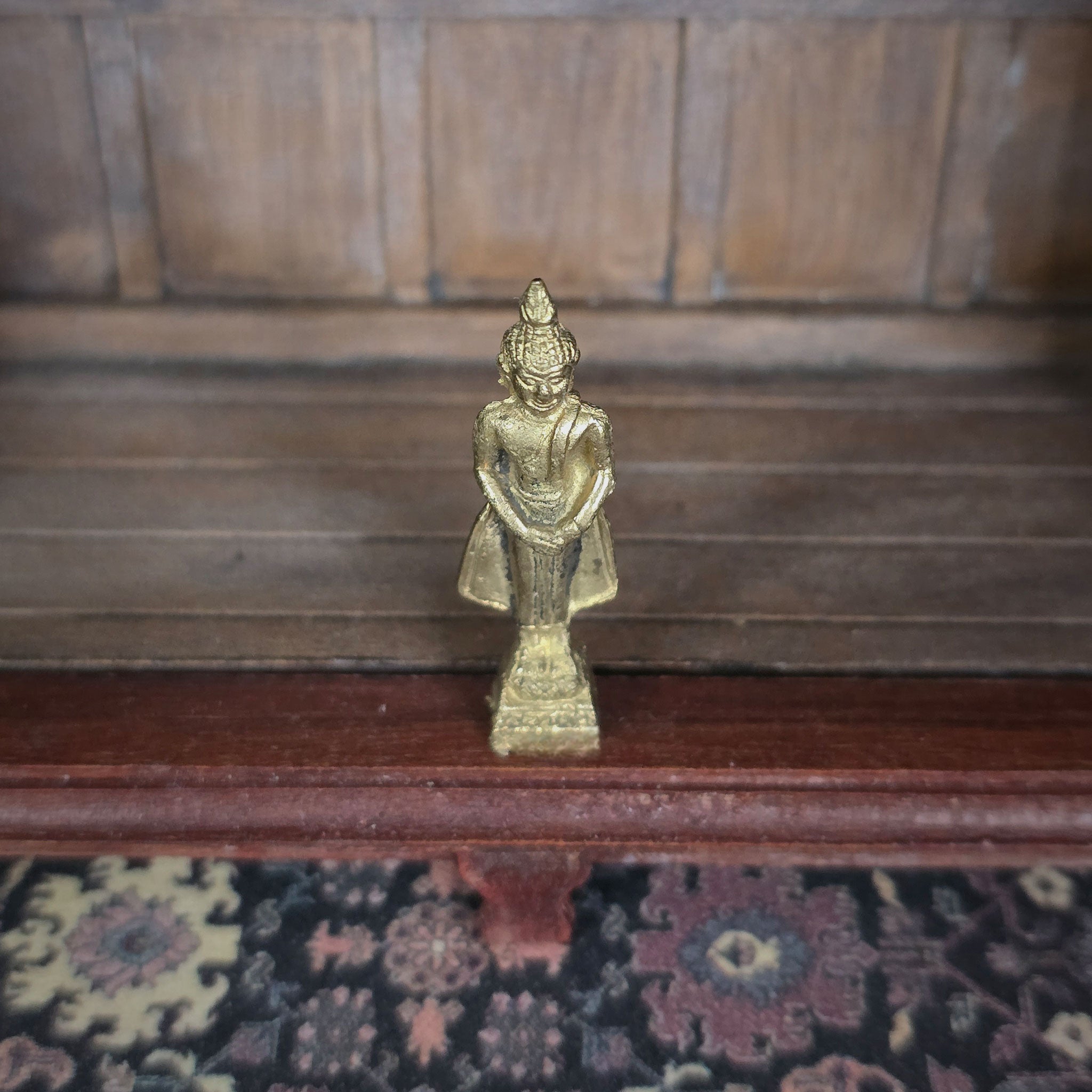 Gold statue on a wooden surface with a patterned rug below