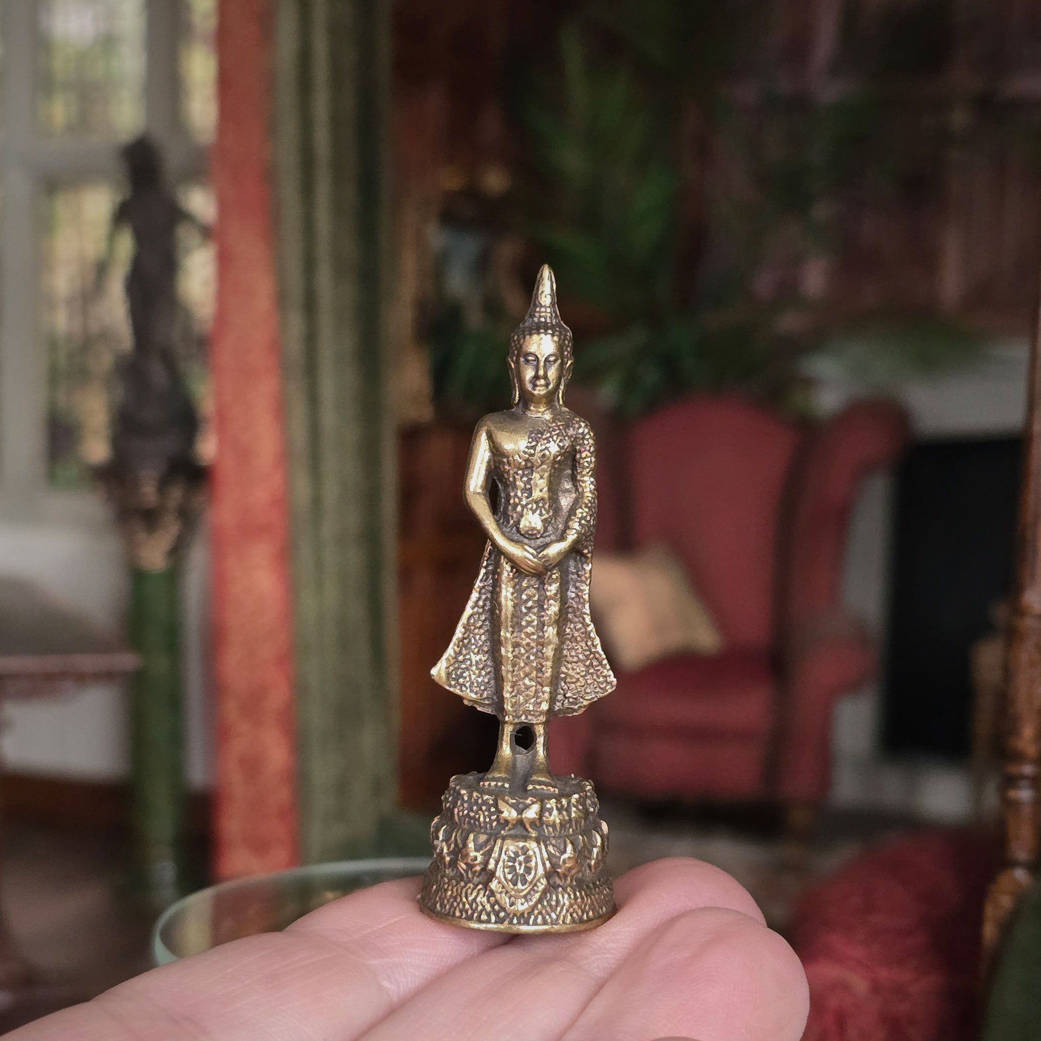 Small ornate statue held in a hand with a blurred indoor background