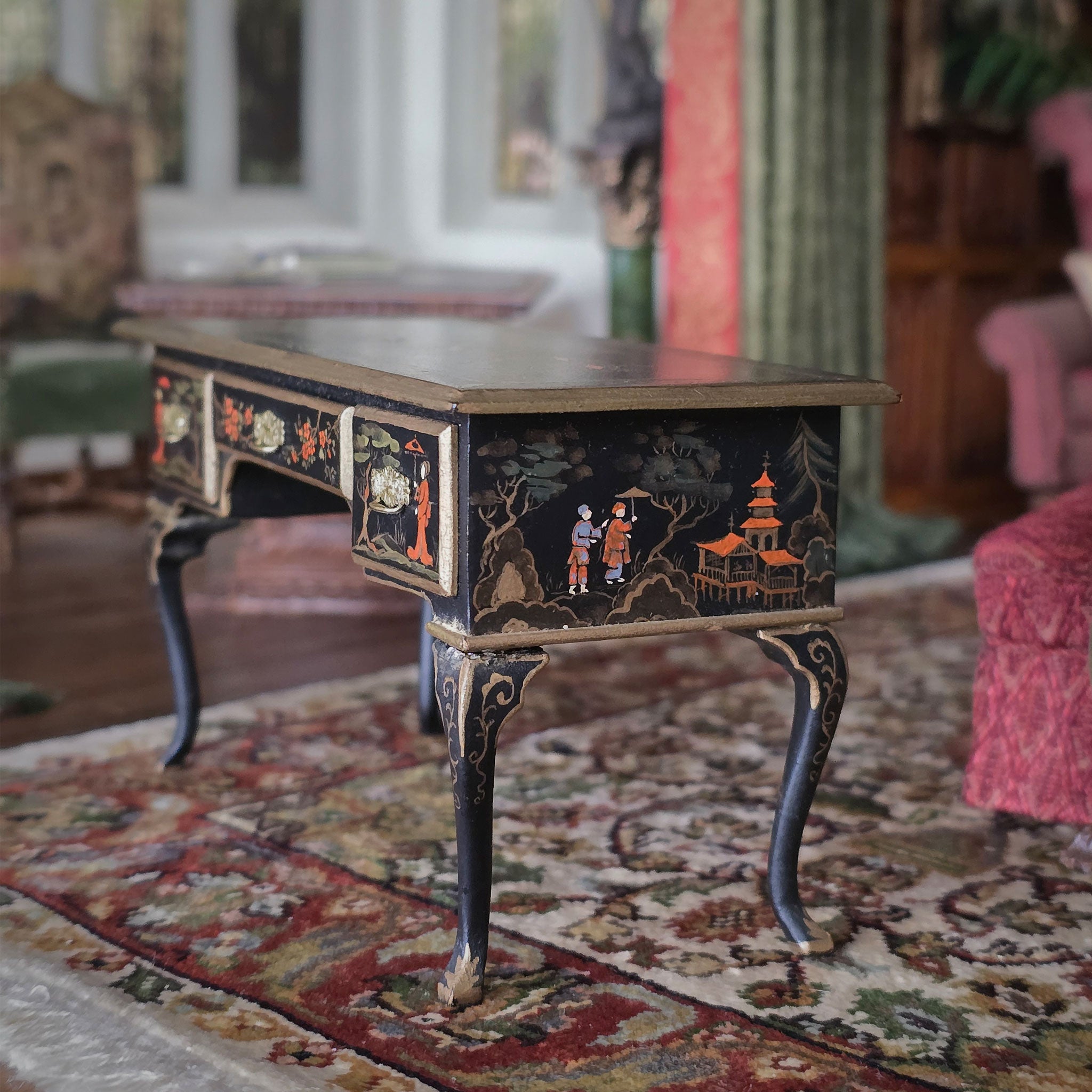 Decorative chinoiserie miniature desk with intricate designs on a patterned rug
