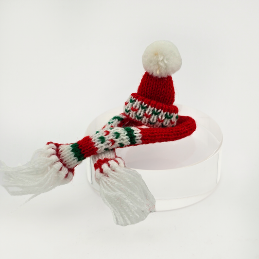 Dollhouse miniature  Knitted red hat with a white pom-pom and green, red, and white striped scarf on a white background