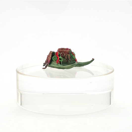 pair of Dollhouse miniature Decorative green and red elves shoes on a clear stand against a white background