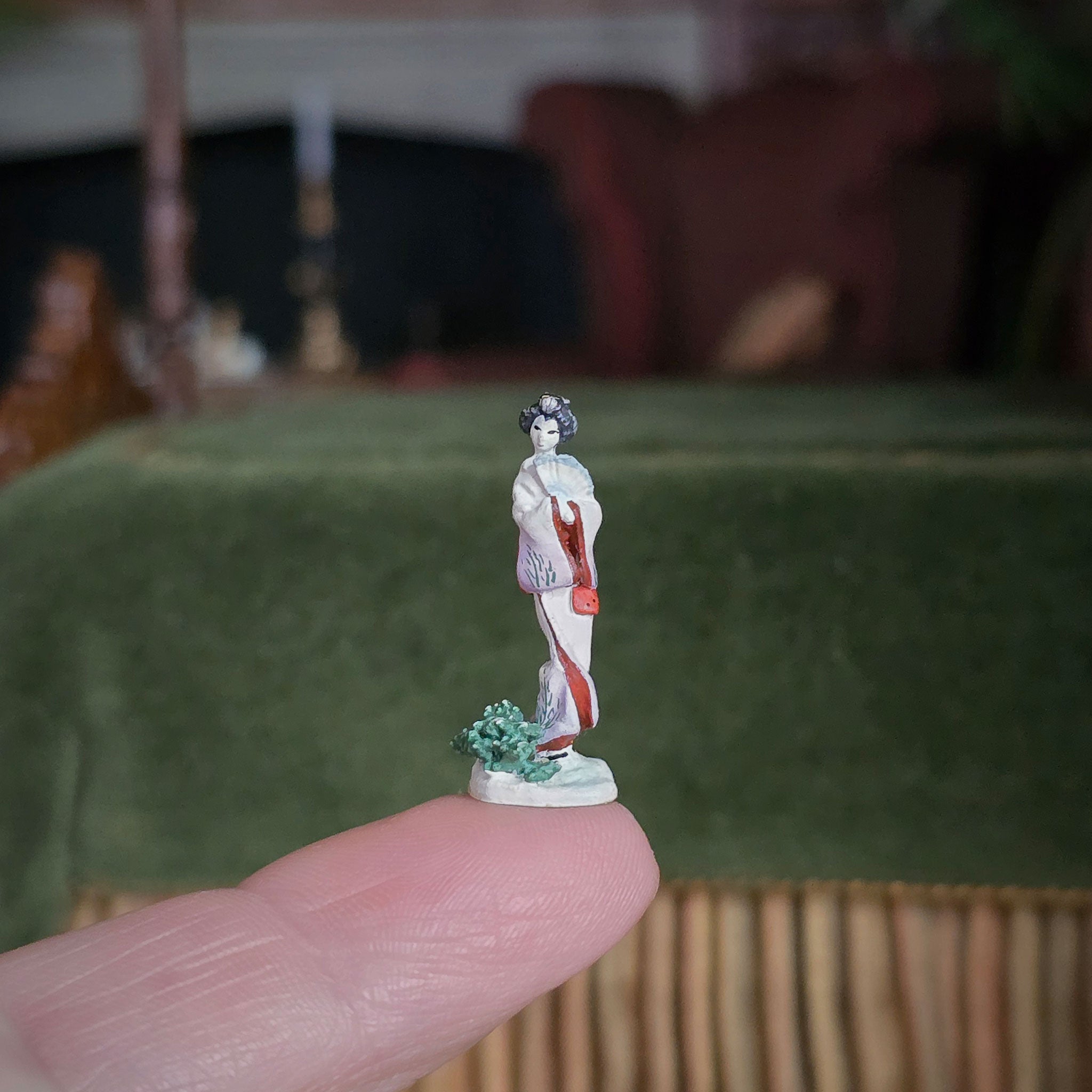 Small figurine held between fingers with a blurred background