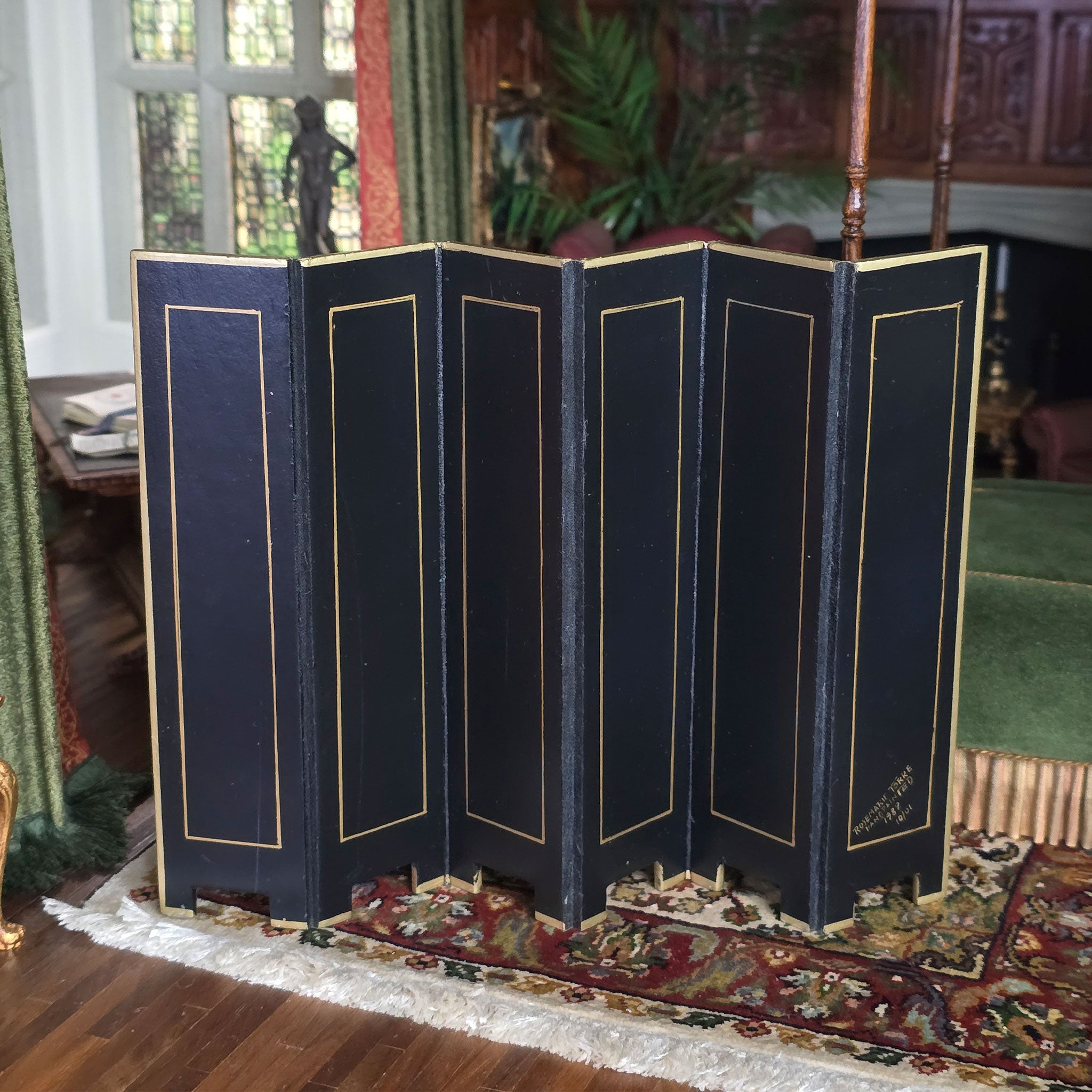 Black folding screen with gold trim in a room with decorative elements