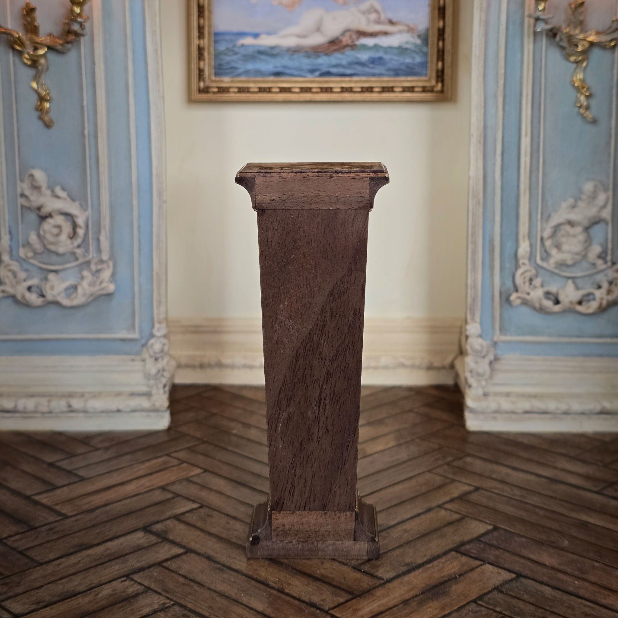 Backside of wooden pedestal in a room with decorative furniture and a painting on the wall.
