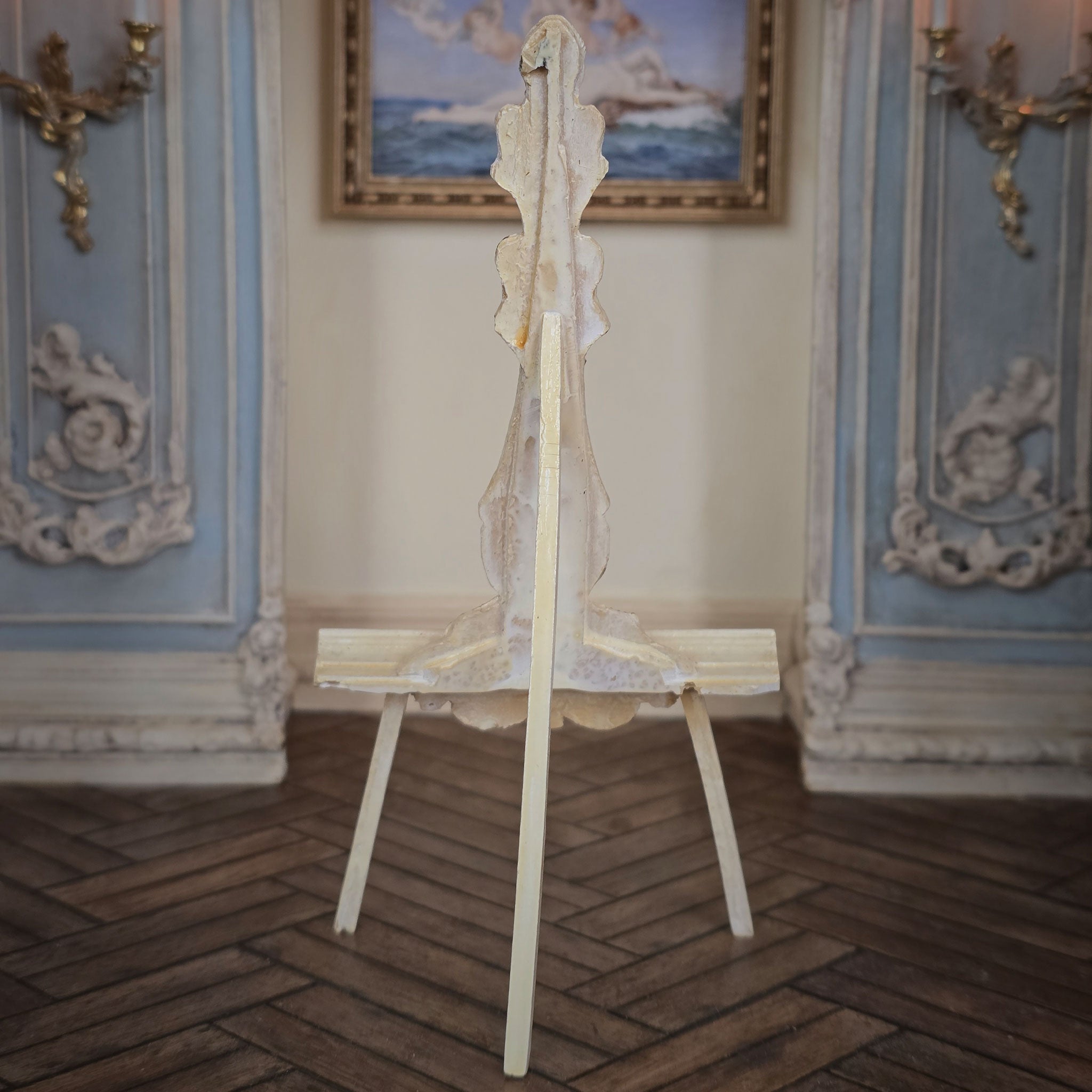 Back of wooden easel in an ornate room.