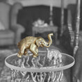 Load image into Gallery viewer, Two small elephant figurines on a round metallic surface with a blurred background
