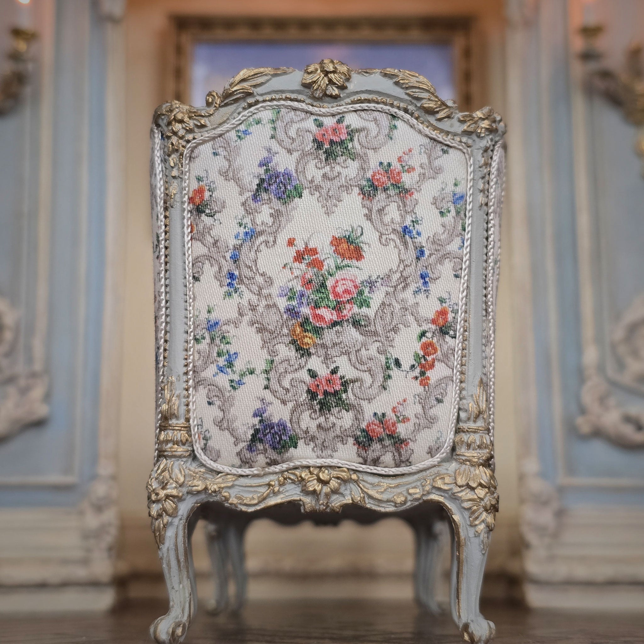 Decorative chaise with floral patterns and gold accents in an elegant room.