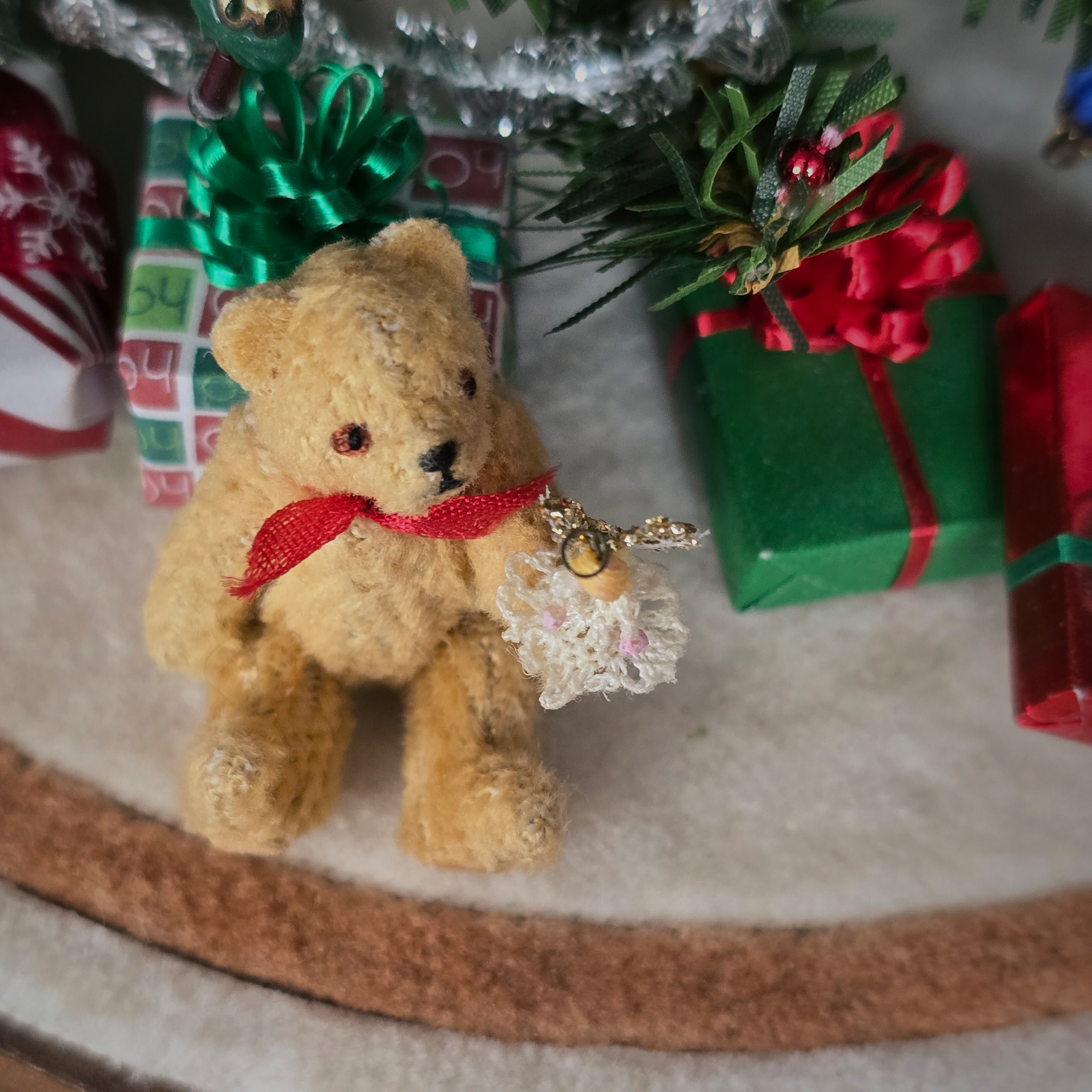 tiny angel tree topper for Christmas in the paw of a toy teddy bear